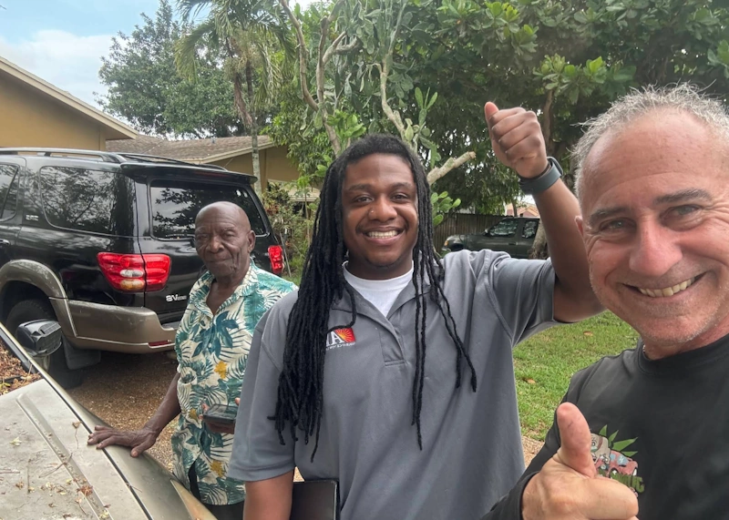 Three men standing near vehicles, serving as an illustrative guide with tips for spotting a junk car scammer.