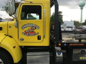 A yellow Junk Yard Dog tow truck offering cash for junk cars in Miami Beach.