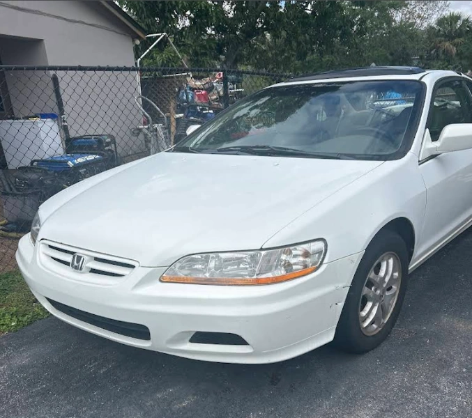 A white sedan parked in a driveway ready for Fort Lauderdale junk car pickup.