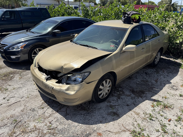A gold-colored sedan showing significant front-end collision damage, a helpful visual example for owners looking to sell a damaged Toyota Camry in Lake Worth Beach.