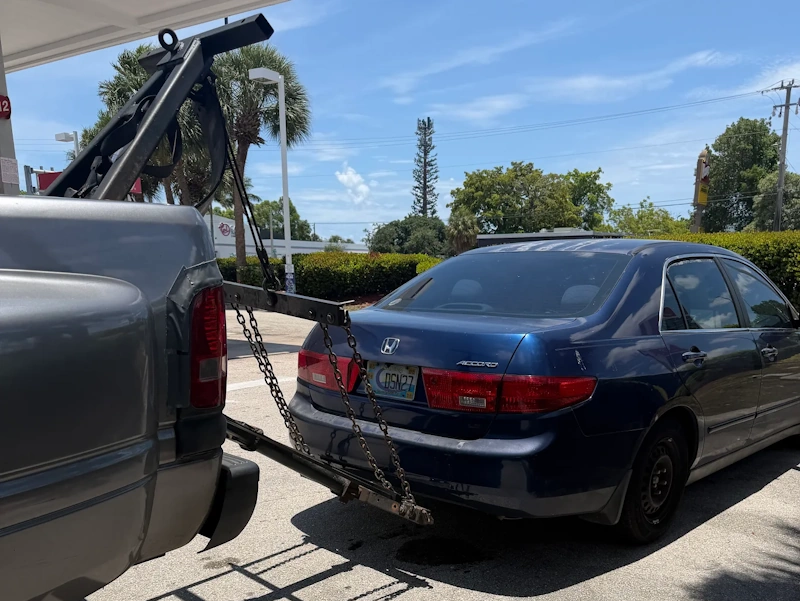 A Honda Accord being hooked up to a gray tow truck, representing a quick process to trade a broken car for cash in Fort Lauderdale.