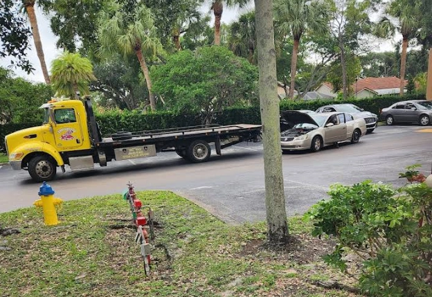 A tow truck preparing to load a sedan, demonstrating important things to do before selling a junk car in Coral Springs.