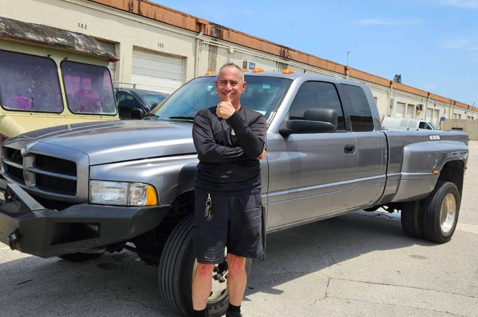Man giving a thumbs up next to a silver Dodge Ram truck sold for cash for junk trucks South Florida