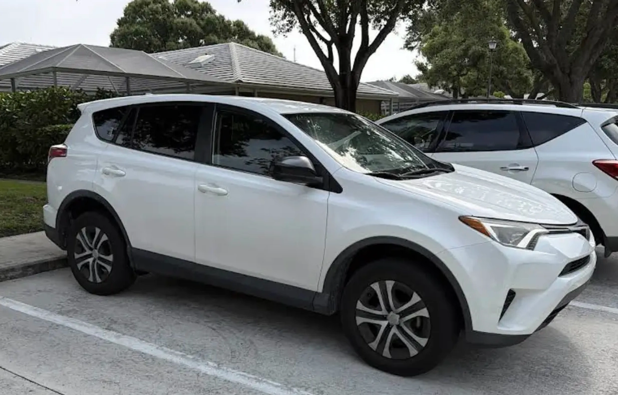 A white Toyota RAV4 LE, a common vehicle prone to specific wear points in South Florida like paint oxidation and interior sun damage, is shown.