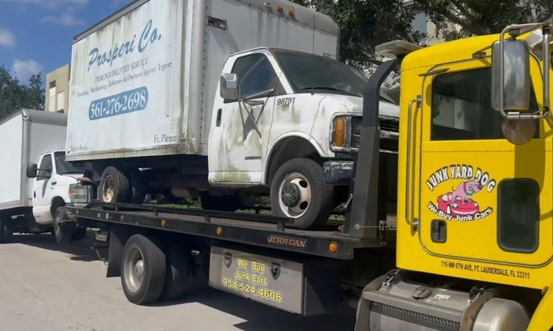 Flatbed tow truck picking up an old junk truck in Fort Lauderdale for cash.